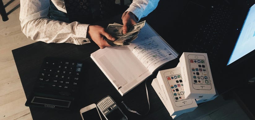 Persona Contando Dinero Con Teléfonos Inteligentes En La Parte Delantera De La Mesa